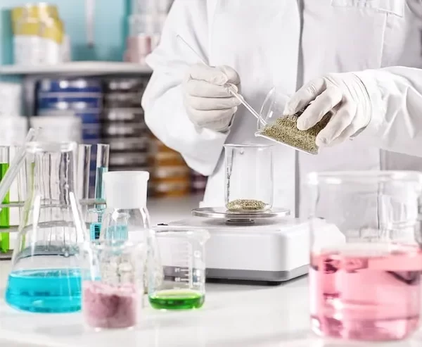 worker-surrounded-with-glass-beakers-filled-with-colorful-liquid_273609-13425